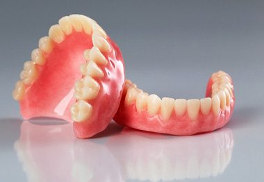 Set of dentures on a reflective gray surface