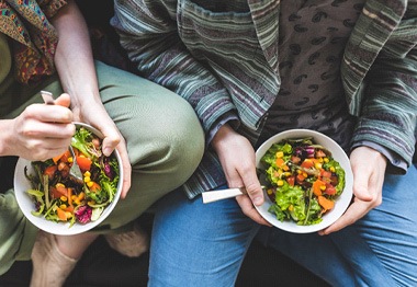 Bird’s eye view of a man and a woman holding salads in their laps